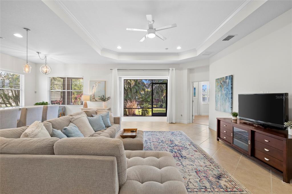 A living room features a large sectional sofa, a patterned rug, and a television console — 4623 CLAREMONT PARK DRIVE, BRADENTON, FL