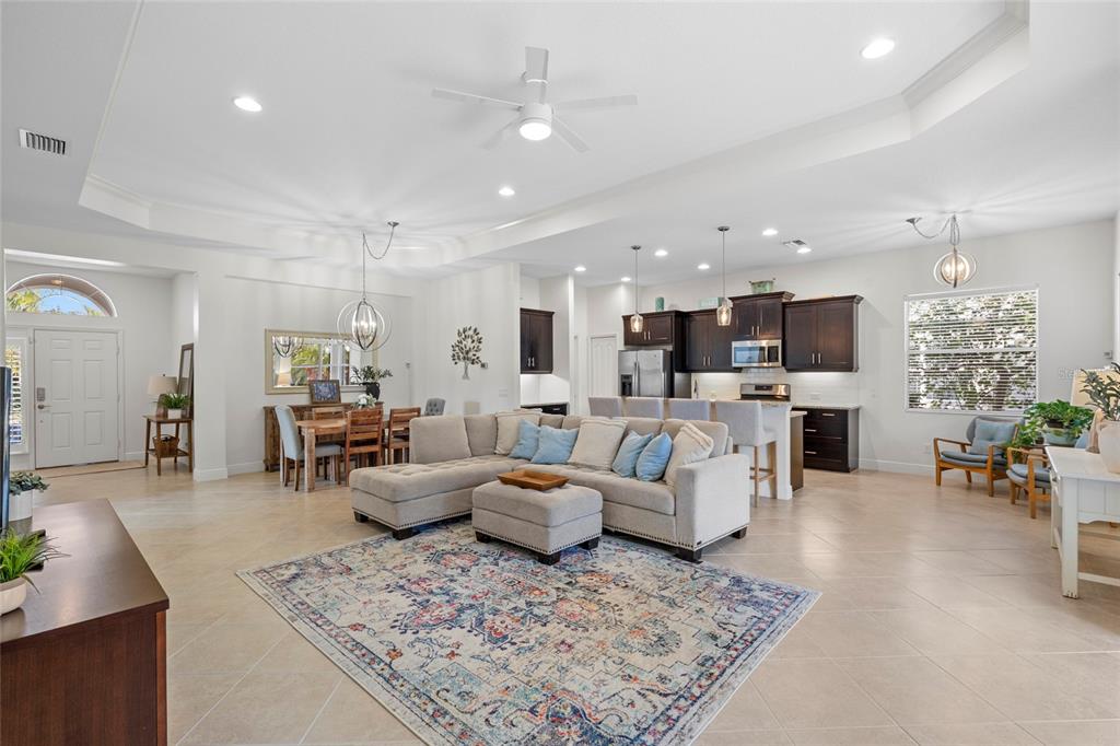 An open-concept living room and kitchen featuring tile floors, a sectional sofa, and dark cabinetry — 4623 CLAREMONT PARK DRIVE, BRADENTON, FL