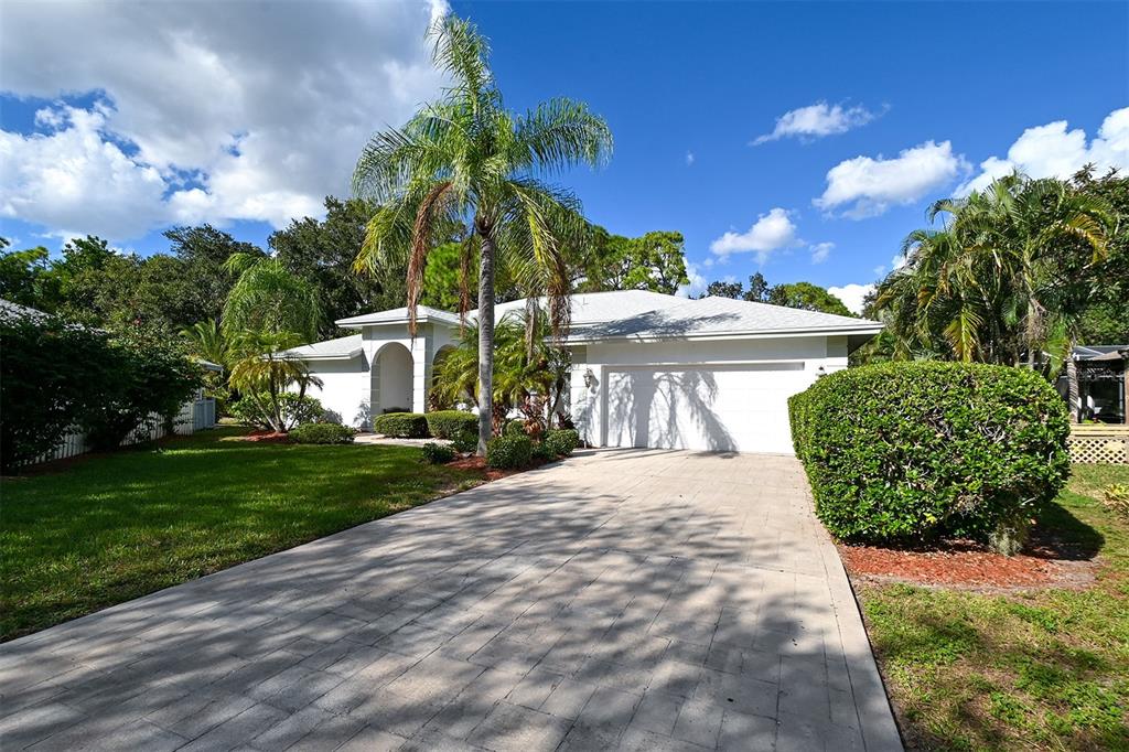 A single-story house with a white exterior, a paved driveway, and several palm trees — 3866 SURREY COURT, SARASOTA, FL