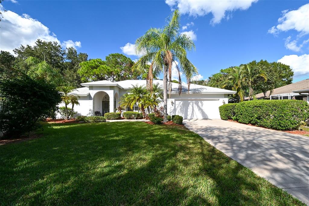 A white single-story house with a palm tree, green lawn, and a concrete driveway — 3866 SURREY COURT, SARASOTA, FL