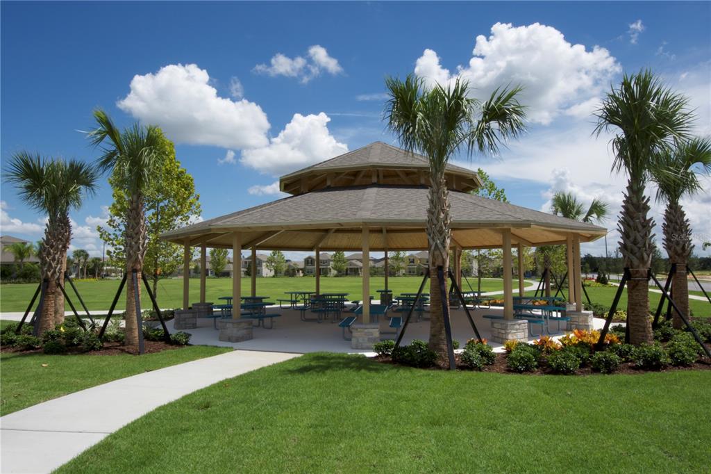 A large, octagonal wooden gazebo sits in a grassy park surrounded by palm trees — 11265 HOLLOW BAY DRIVE, WINTER GARDEN, FL