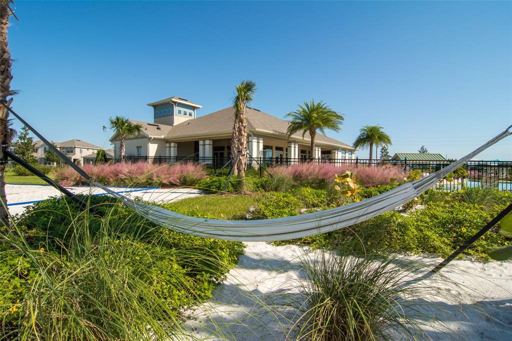 A white hammock hangs over a sandy area in front of a community clubhouse building — 11265 HOLLOW BAY DRIVE, WINTER GARDEN, FL