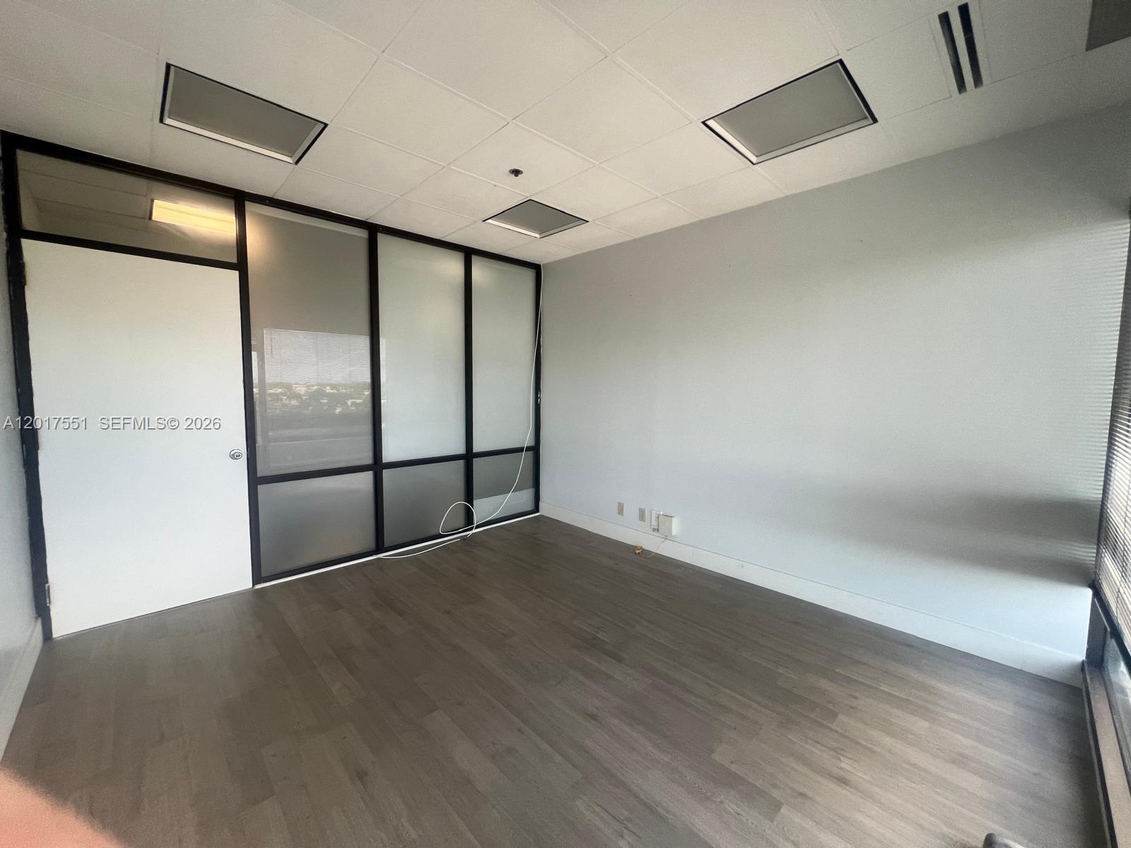 An empty office space features gray wood-look flooring, white walls, and a glass partition wall — 900 W 49th St Suite546, Hialeah FL 33012, HIALEAH, FL