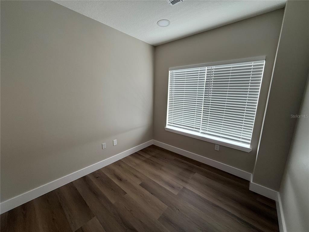 An empty room features light-colored walls, wood-look flooring, and a window with white blinds — 3699 AIRFIELD DRIVE W, LAKELAND, FL