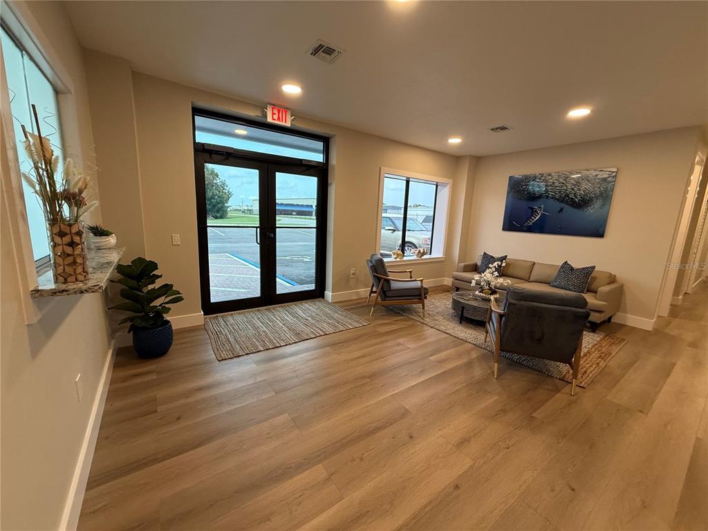 A lobby area features wood-look flooring, a seating arrangement, and double glass exit doors — 3699 AIRFIELD DRIVE W, LAKELAND, FL