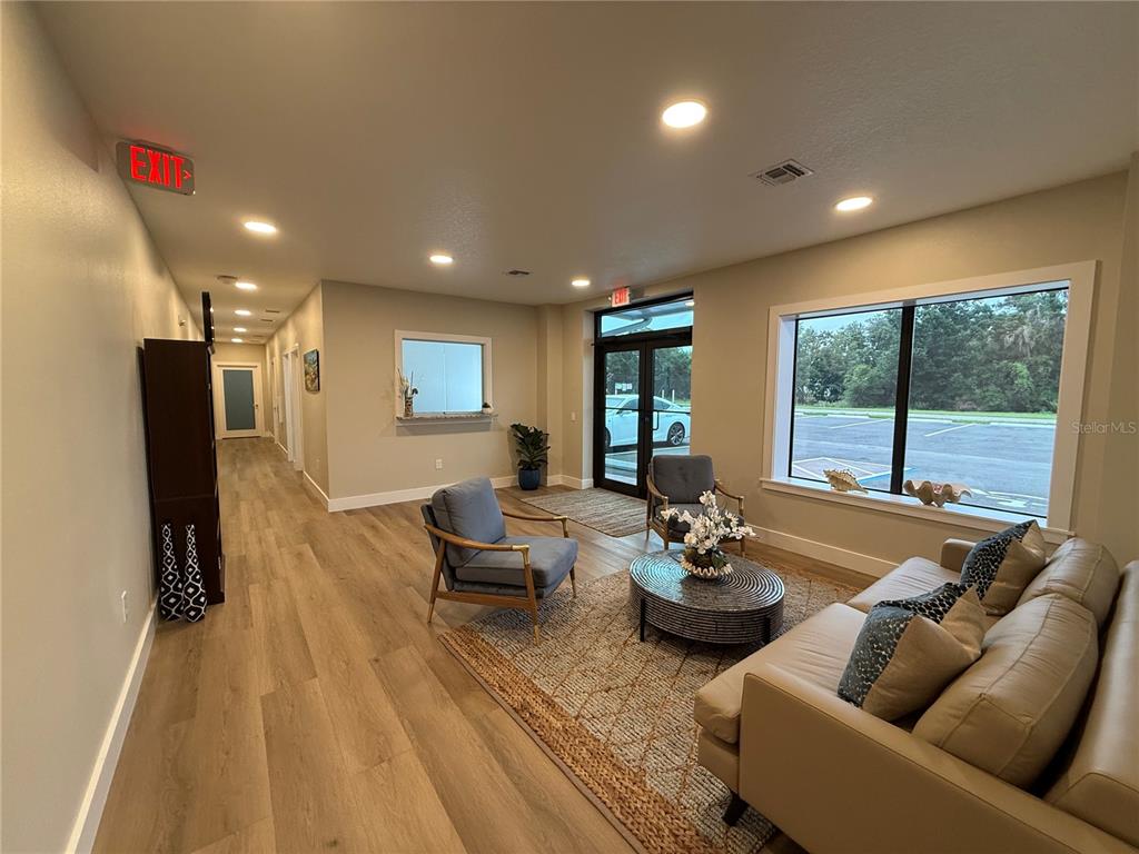 A lobby features light wood flooring, a seating area with a sofa, and glass entry doors — 3699 AIRFIELD DRIVE W, LAKELAND, FL