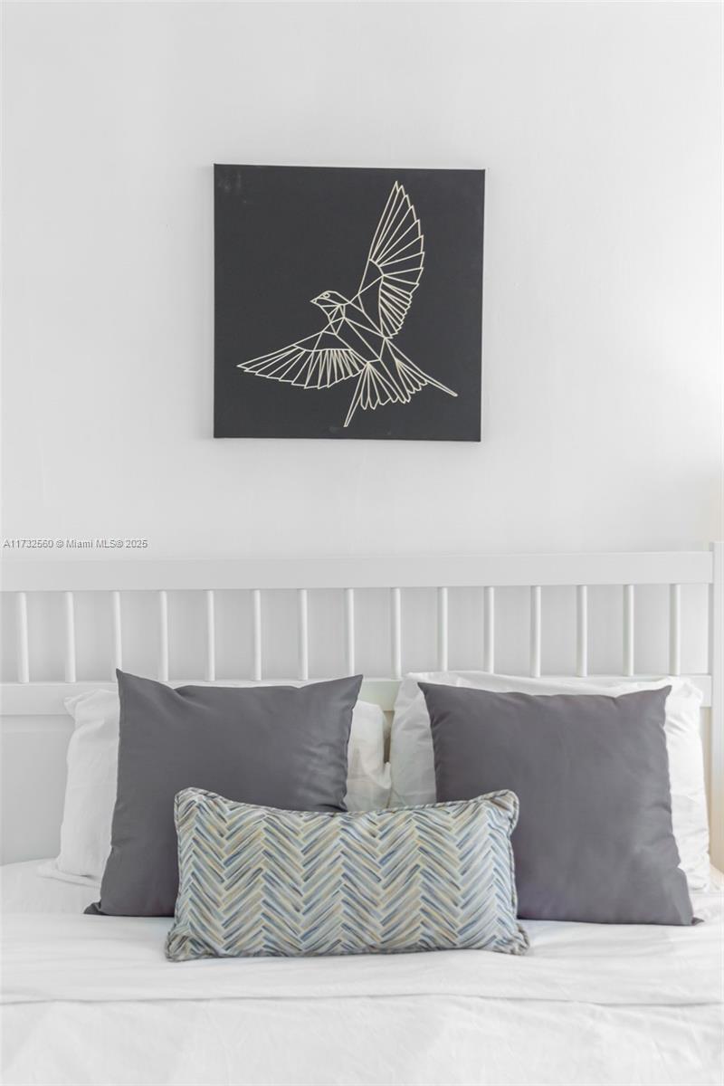 A white bed with gray pillows and a geometric bird art piece on the wall — 5445 Collins Ave # 1623, Miami Beach FL 33140, MIAMI BEACH, FL