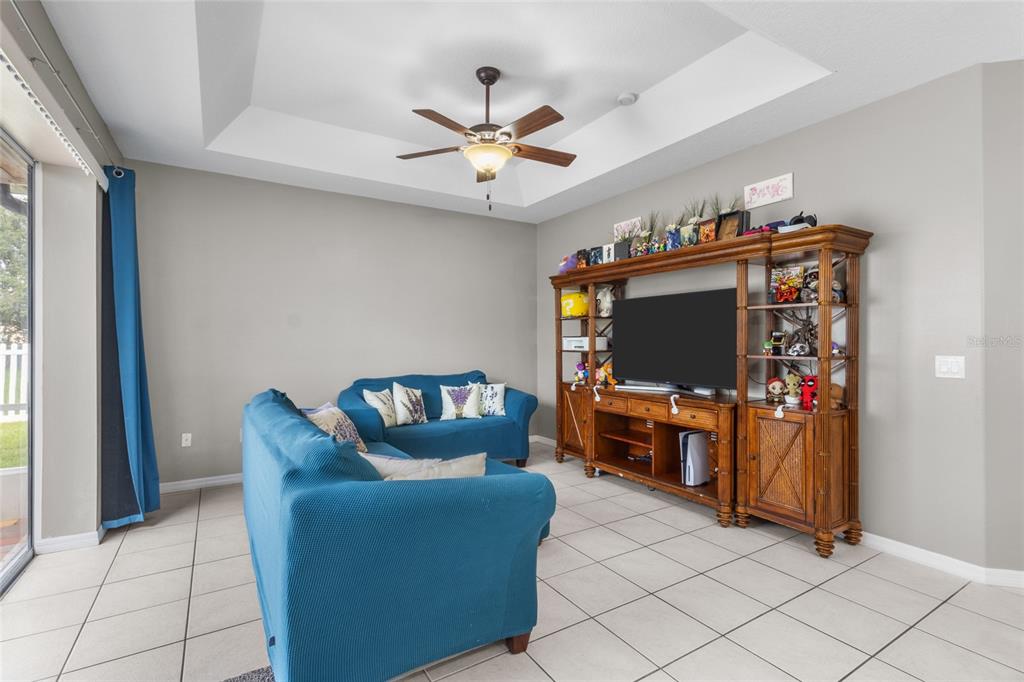 A living room features blue sofas, a wooden entertainment center, and a tray ceiling — 111 141ST COURT NE, BRADENTON, FL