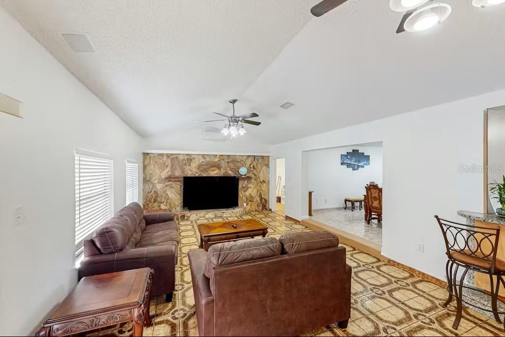 A living room features a stone fireplace, tile flooring, and brown leather furniture — 6223 TRAVIS BOULEVARD, TAMPA, FL