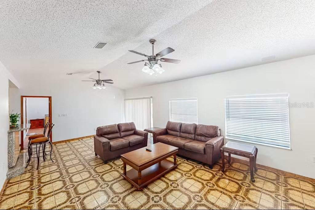 A living room features brown leather furniture, a wooden coffee table, and patterned tile flooring — 6223 TRAVIS BOULEVARD, TAMPA, FL