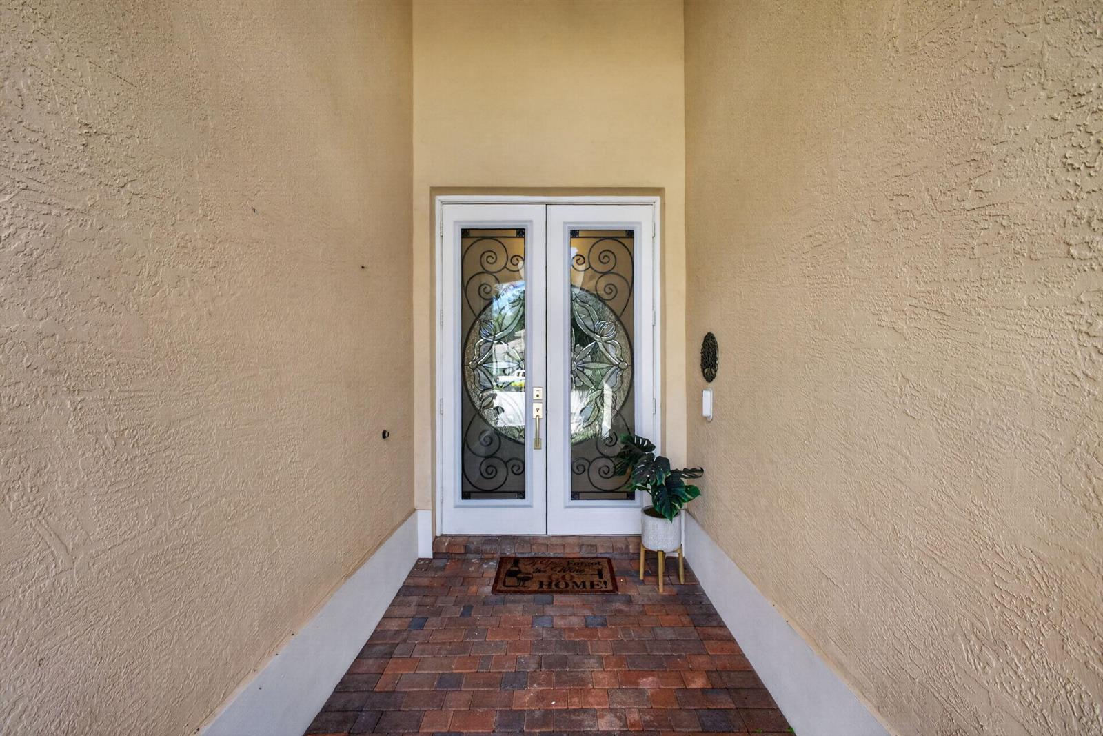 A front entryway features double glass-paneled doors, a brick floor, and tan stucco walls — 8642 Plum Cay, Royal Palm Beach FL 33411, ROYAL PALM BEACH, FL