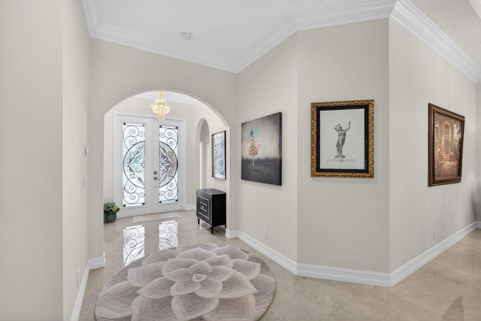 A bright foyer features a round rug, arched entryway, double glass doors, and wall art — 8642 Plum Cay, Royal Palm Beach FL 33411, ROYAL PALM BEACH, FL