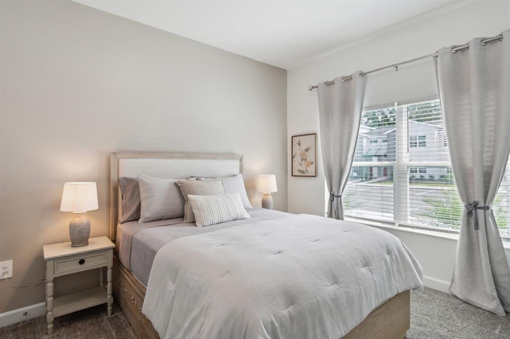 A bedroom features a bed with light bedding, two nightstands with lamps, and gray curtains — 2440 READING TRAIL, KISSIMMEE, FL