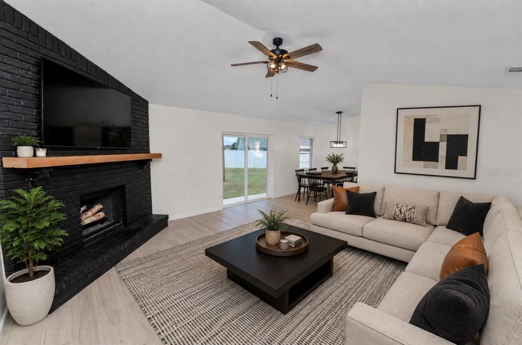 A living room features a black brick fireplace, a sectional sofa, and a dining area — 3664 WILLOW WISP DRIVE S, LAKELAND, FL