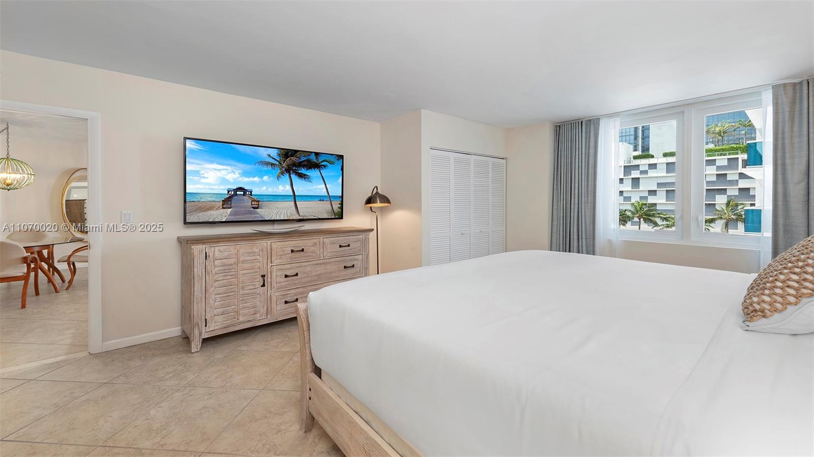 A bedroom features a large bed, a wooden dresser with a television, and window views — 2301 Collins Ave # 301, Miami Beach FL 33139, MIAMI BEACH, FL