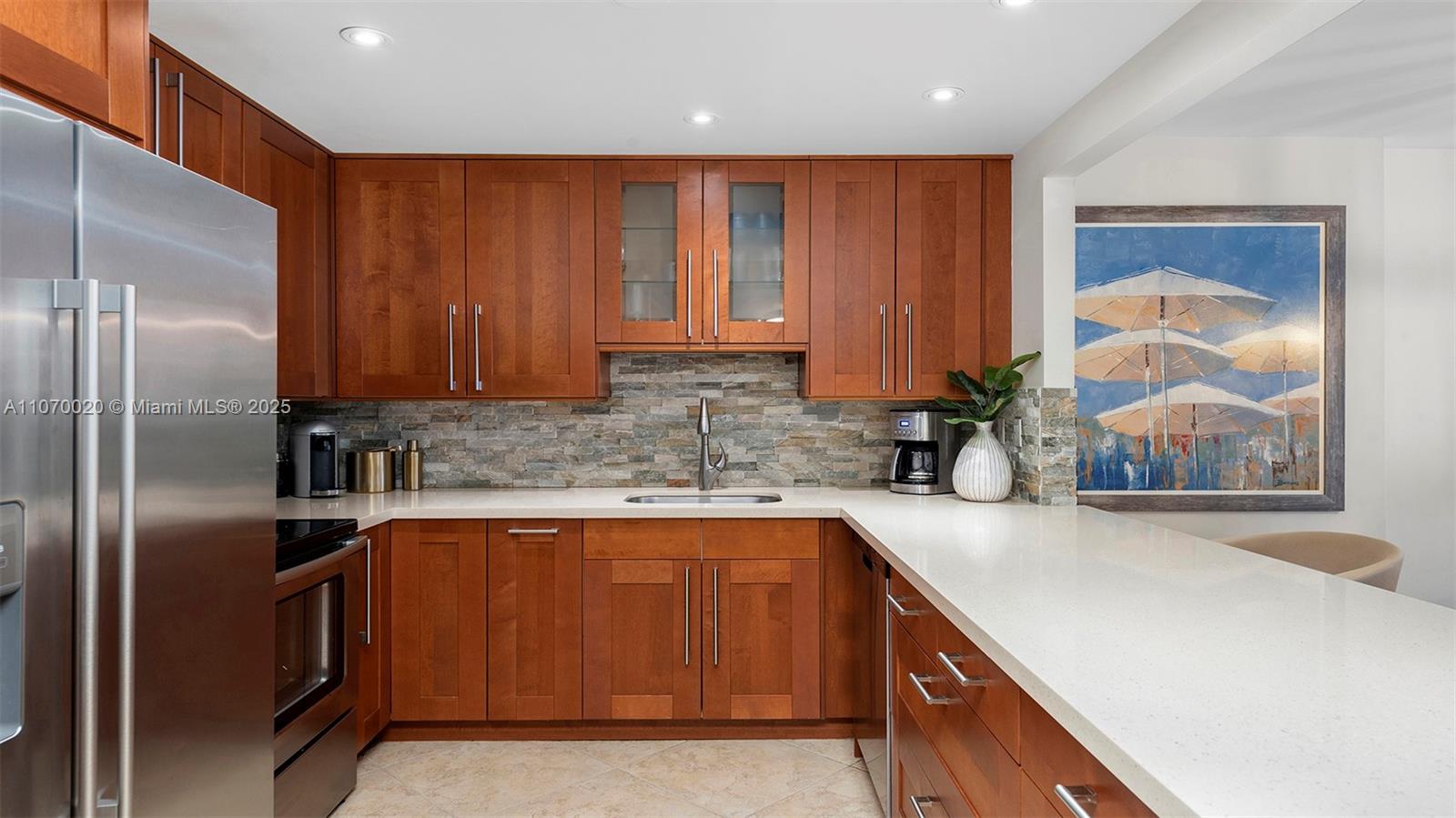 A kitchen features wood cabinets, stone backsplash, stainless steel appliances, and white countertops — 2301 Collins Ave # 301, Miami Beach FL 33139, MIAMI BEACH, FL