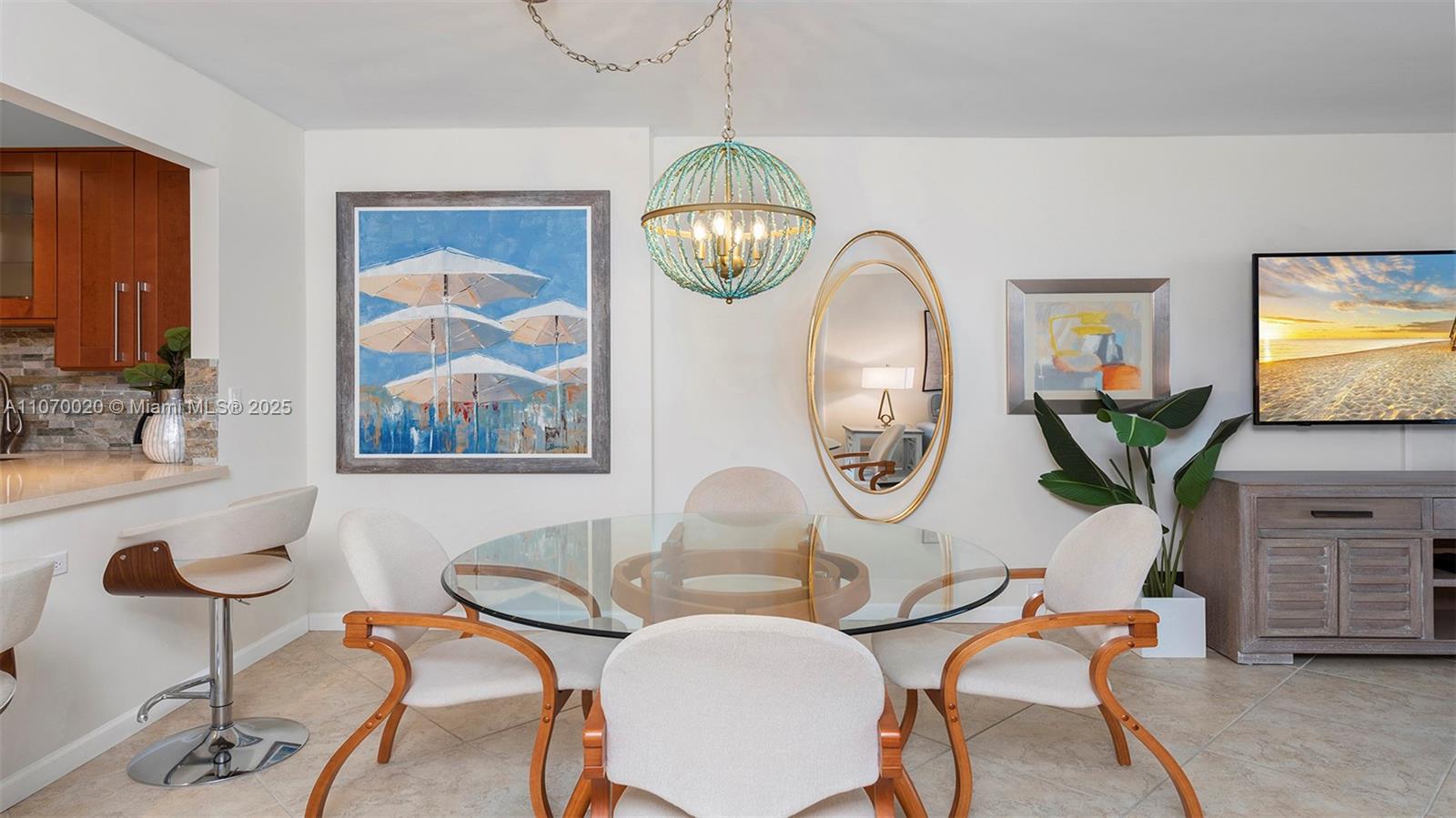 A dining area features a glass-topped table, four chairs, a beaded chandelier, and wall art — 2301 Collins Ave # 301, Miami Beach FL 33139, MIAMI BEACH, FL