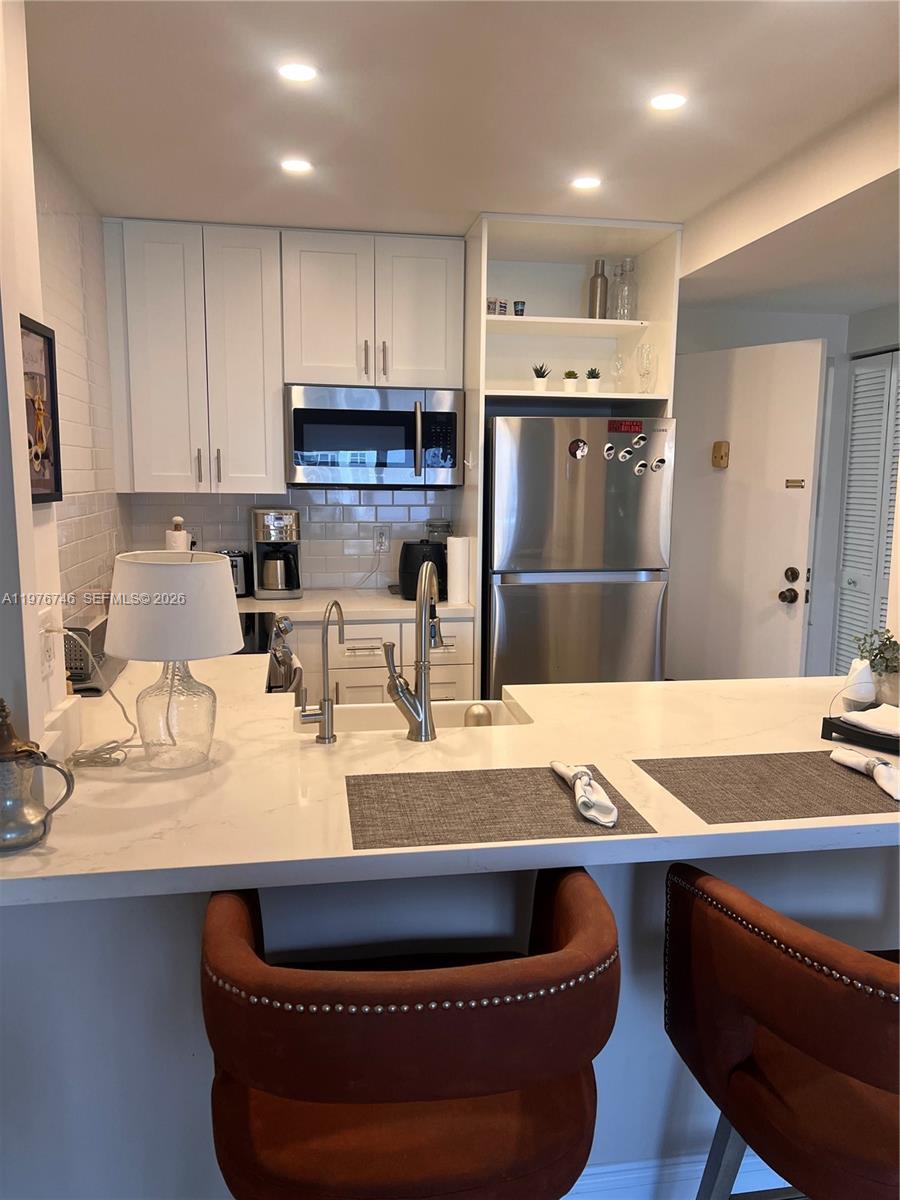 A kitchen features white cabinetry, stainless steel appliances, and a white quartz breakfast bar — 400 N Riverside Dr # 410, Pompano Beach FL 33062, POMPANO BEACH, FL