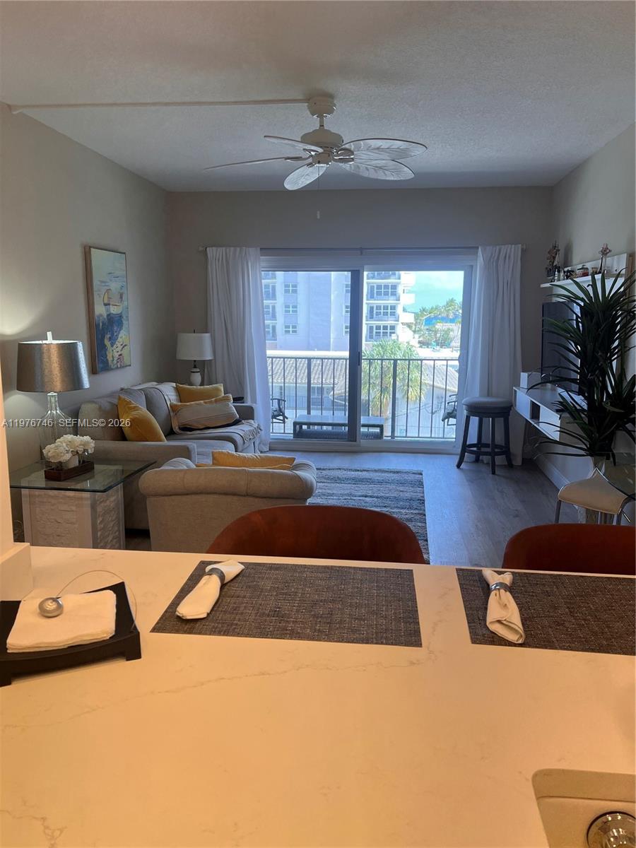 A living room with a sofa, ceiling fan, and sliding glass doors leading to a balcony — 400 N Riverside Dr # 410, Pompano Beach FL 33062, POMPANO BEACH, FL