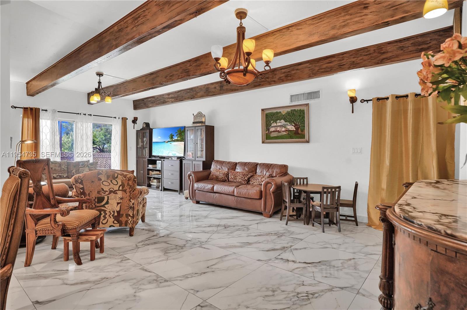 A living room features exposed wood ceiling beams, marble-look tile flooring, and a leather sofa — 16750 NE 10th Ave, North Miami Beach FL 33162, NORTH MIAMI BEACH, FL