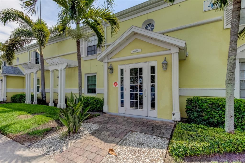 An aerial view shows a residential complex with a central pool surrounding a small lake — 5092 BEACH DRIVE SE UNIT A, ST PETERSBURG, FL