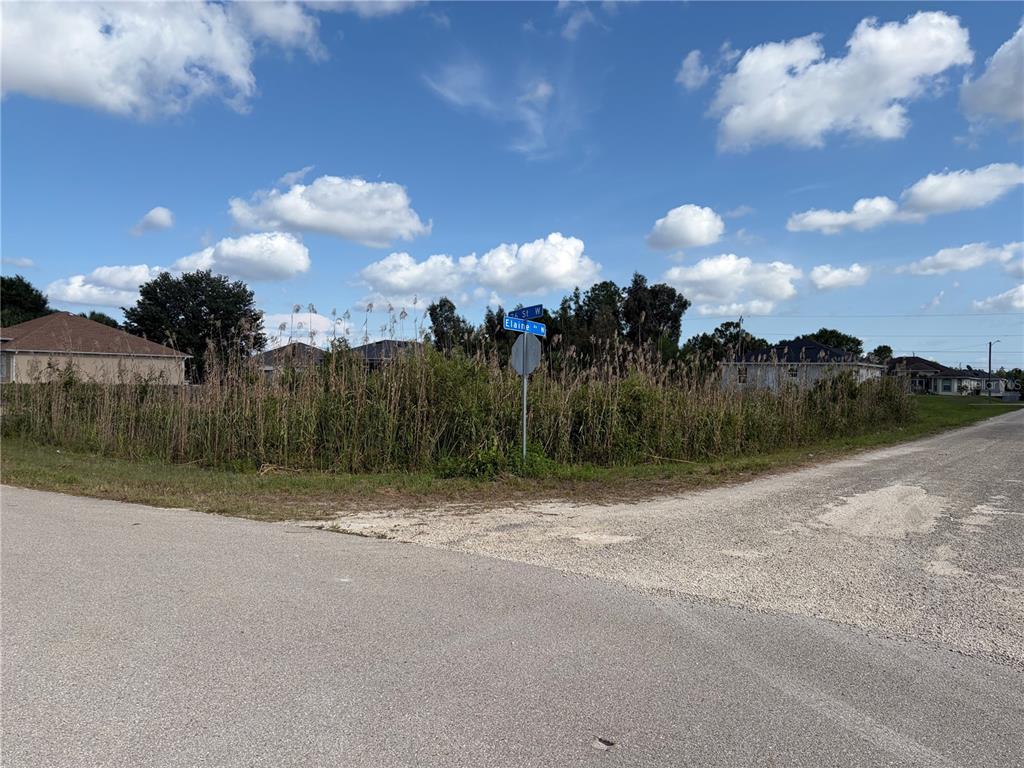 A cleared, vacant residential lot features dark soil and scattered vegetation under a blue sky — 2619 26TH STREET W, LEHIGH ACRES, FL