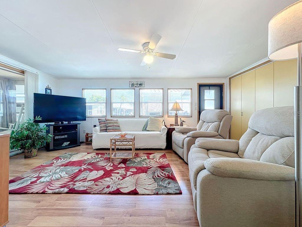 A living room features a red floral rug, a white sofa, and two beige recliners — 3333 26TH AVENUE E UNIT 1099, BRADENTON, FL