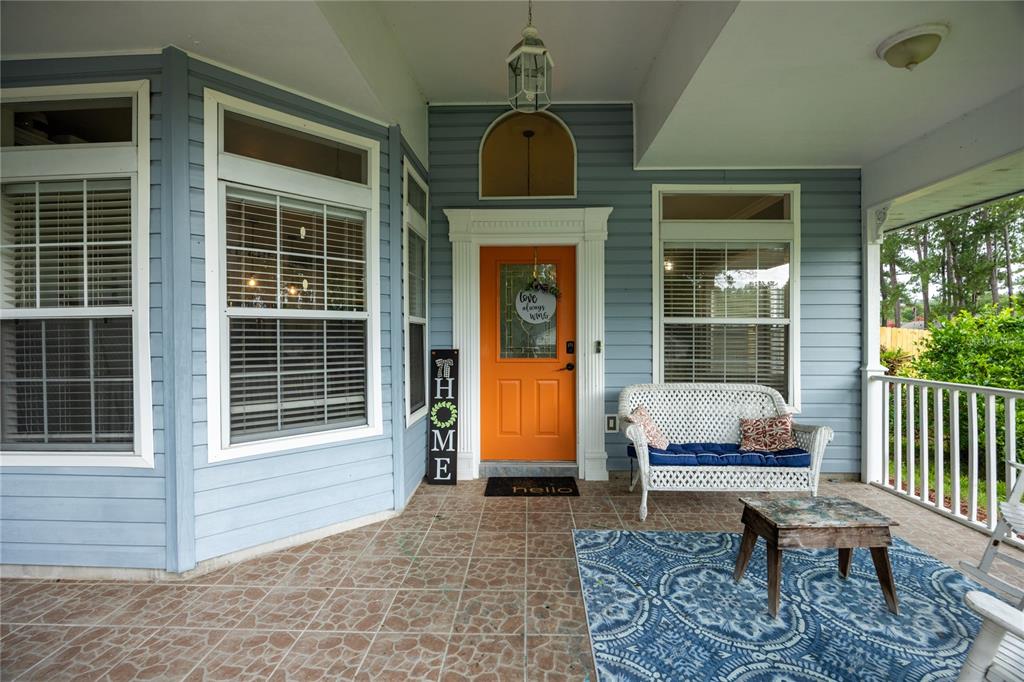 A covered front porch features light blue siding, an orange door, and tiled flooring — 11516 NW 16TH PLACE, GAINESVILLE, FL