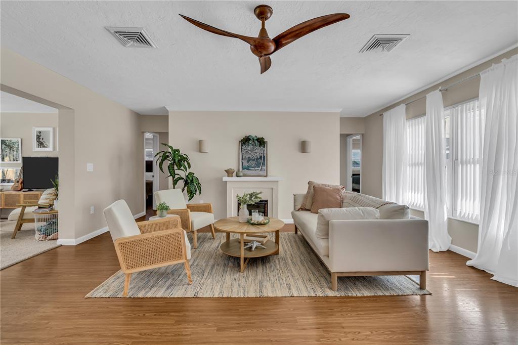 A living room features a fireplace, a wooden ceiling fan, and light-colored furniture on wood floors — 2449 BREAKWATER CIRCLE, SARASOTA, FL