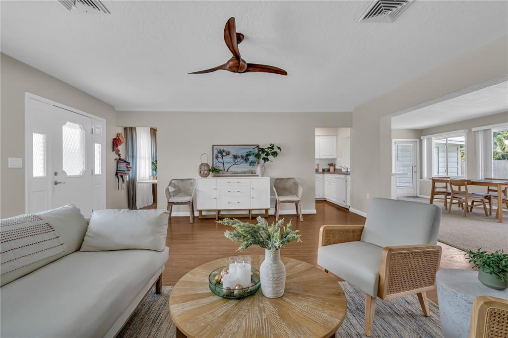 A living room features a light-colored sofa, a round wooden coffee table, and a white sideboard — 2449 BREAKWATER CIRCLE, SARASOTA, FL