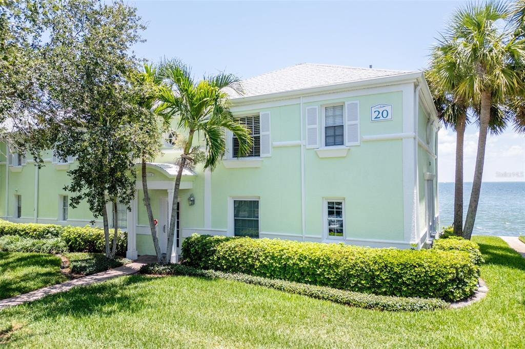 A light green two-story building with a white roof sits beside a body of water — 5118 COQUINA KEY DRIVE SE UNIT C, ST PETERSBURG, FL