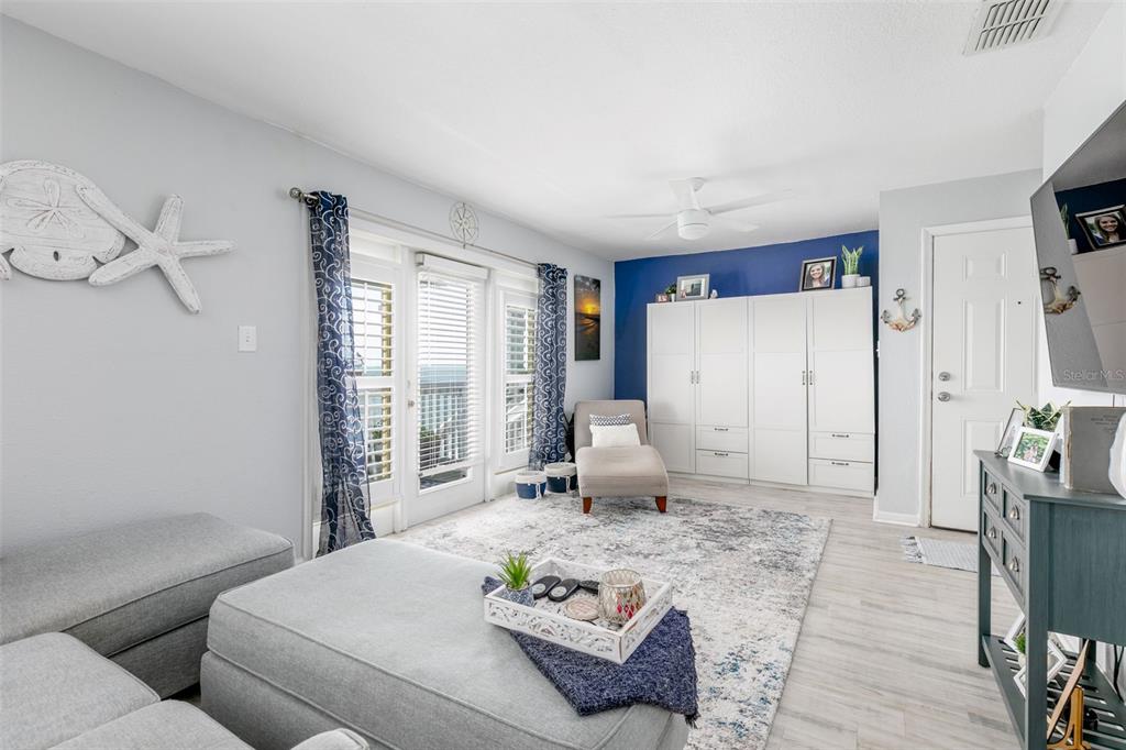 A living room features a grey sectional, a white storage unit, and a blue accent wall — 5118 COQUINA KEY DRIVE SE UNIT C, ST PETERSBURG, FL