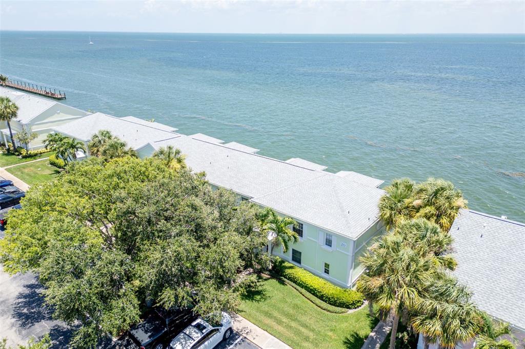 An aerial view shows a light green waterfront building with a gray shingled roof — 5118 COQUINA KEY DRIVE SE UNIT C, ST PETERSBURG, FL