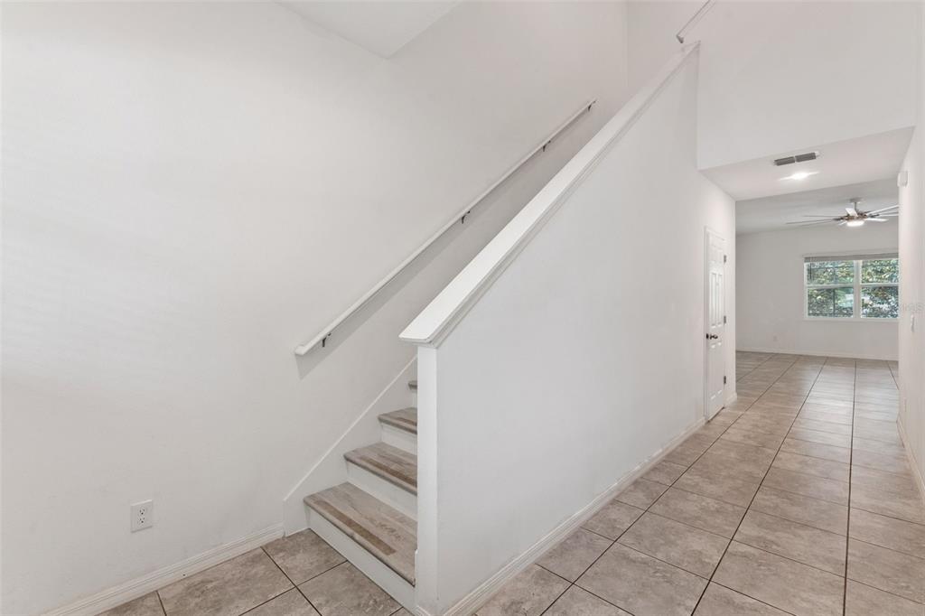 A staircase with light wood treads and white railings leads upward in a tiled hallway — 2265 EMERALD SPRINGS DRIVE, APOPKA, FL