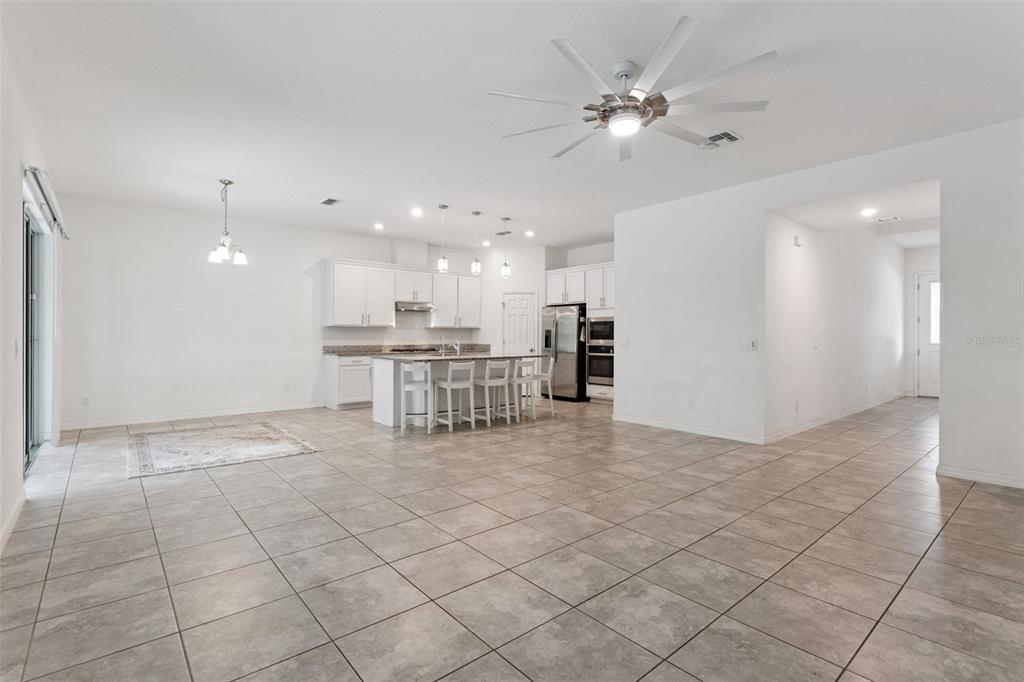 A spacious open-concept kitchen and living area features white cabinetry, a center island, and tile flooring — 2265 EMERALD SPRINGS DRIVE, APOPKA, FL