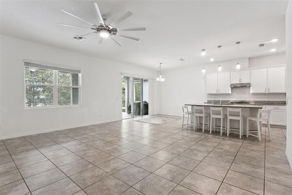 An open-concept kitchen and living area features white cabinets, a granite island, and tile flooring — 2265 EMERALD SPRINGS DRIVE, APOPKA, FL