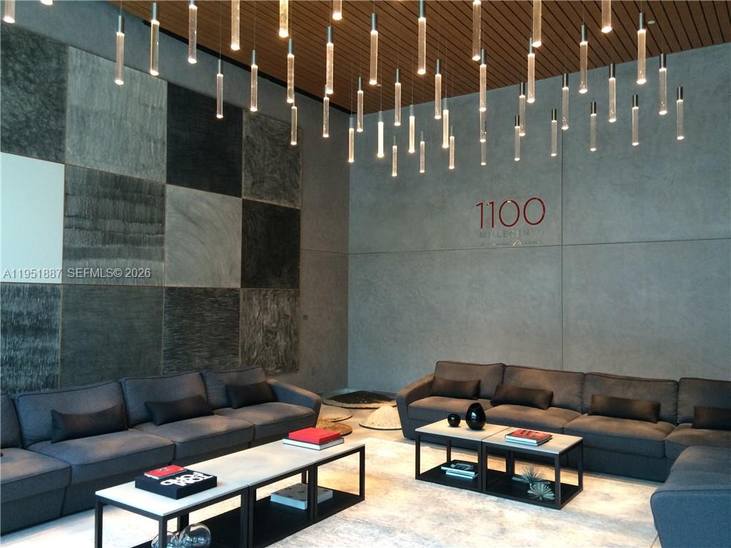 A modern lobby features gray sofas, coffee tables, and a ceiling with hanging cylindrical lights — 1100 S Miami Ave # 2111, Miami FL 33130, MIAMI, FL