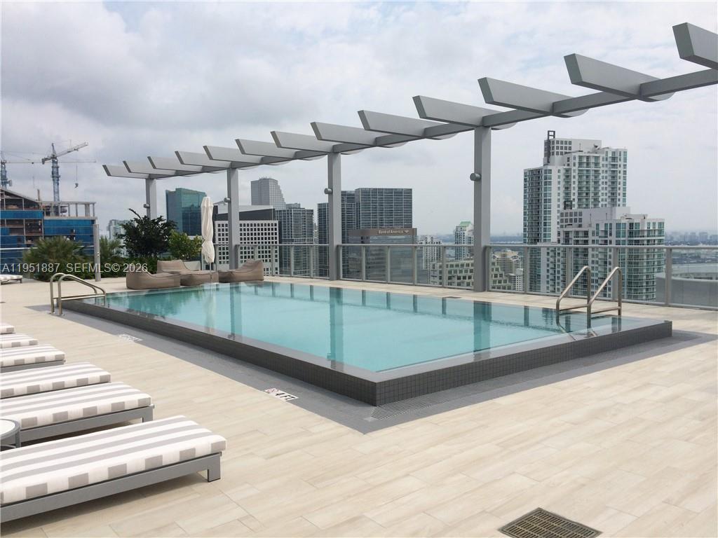 A rooftop swimming pool with lounge chairs and a pergola overlooks a city skyline — 1100 S Miami Ave # 2111, Miami FL 33130, MIAMI, FL