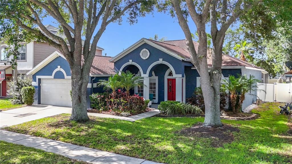 A blue single-story house with a white garage, arched entryway, and a red front door — 1904 CATTLEMAN DRIVE, BRANDON, FL