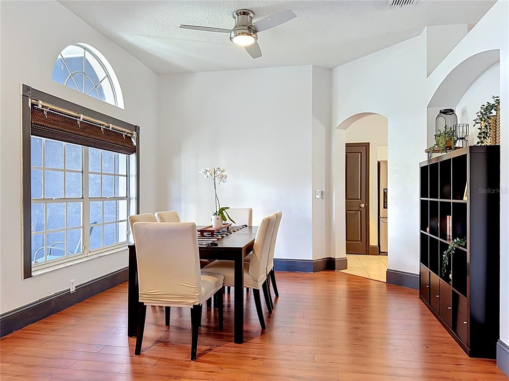 A dining room features a dark wood table with upholstered chairs, hardwood floors, and shelving — 1904 CATTLEMAN DRIVE, BRANDON, FL