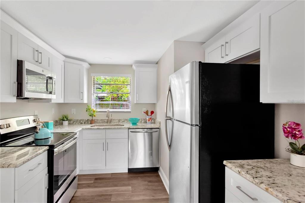 A kitchen features white cabinets, granite countertops, stainless steel appliances, and a black refrigerator — 4105 W MANGO AVENUE, TAMPA, FL