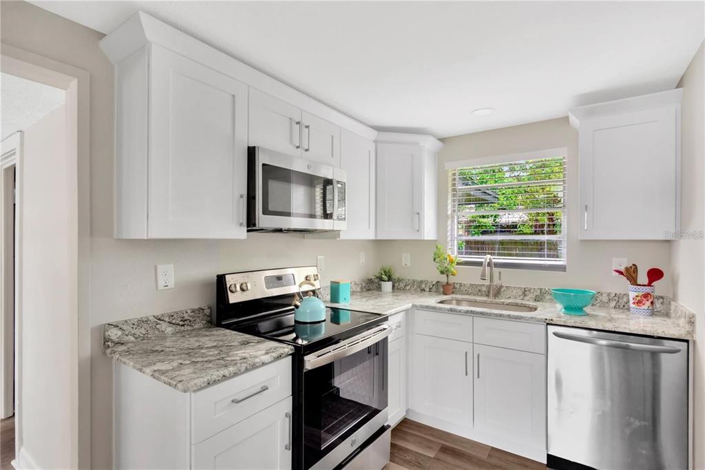 A kitchen with white cabinets, granite countertops, stainless steel appliances, and a window above the sink — 4105 W MANGO AVENUE, TAMPA, FL