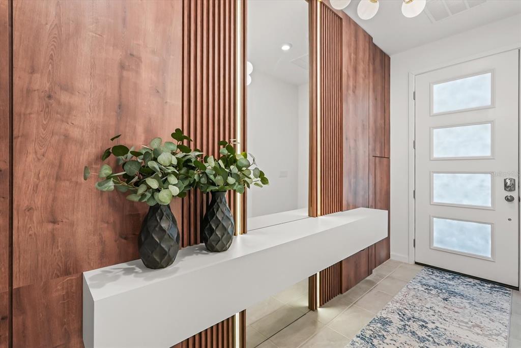 A modern entryway features a floating white console, wood-paneled walls, and vertical accent lighting — 2314 CALM SHORE WAY, KISSIMMEE, FL