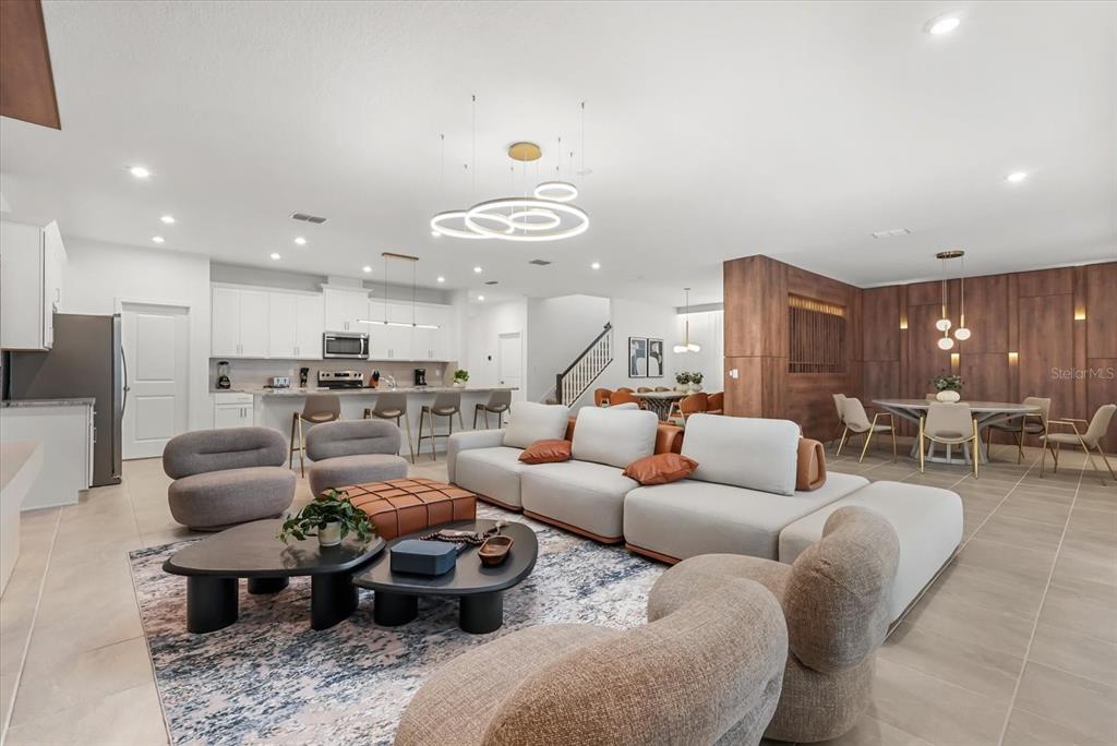 An open-concept living room and kitchen feature a large sectional, modern lighting, and wood paneling — 2314 CALM SHORE WAY, KISSIMMEE, FL