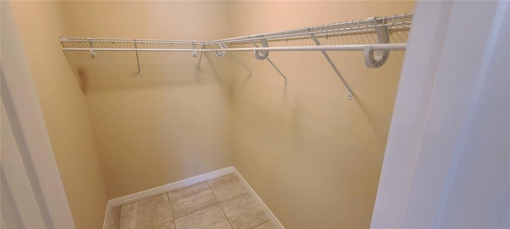 A walk-in closet features beige walls, tile flooring, and white wire shelving — 3858 SW 133RD LOOP, OCALA, FL