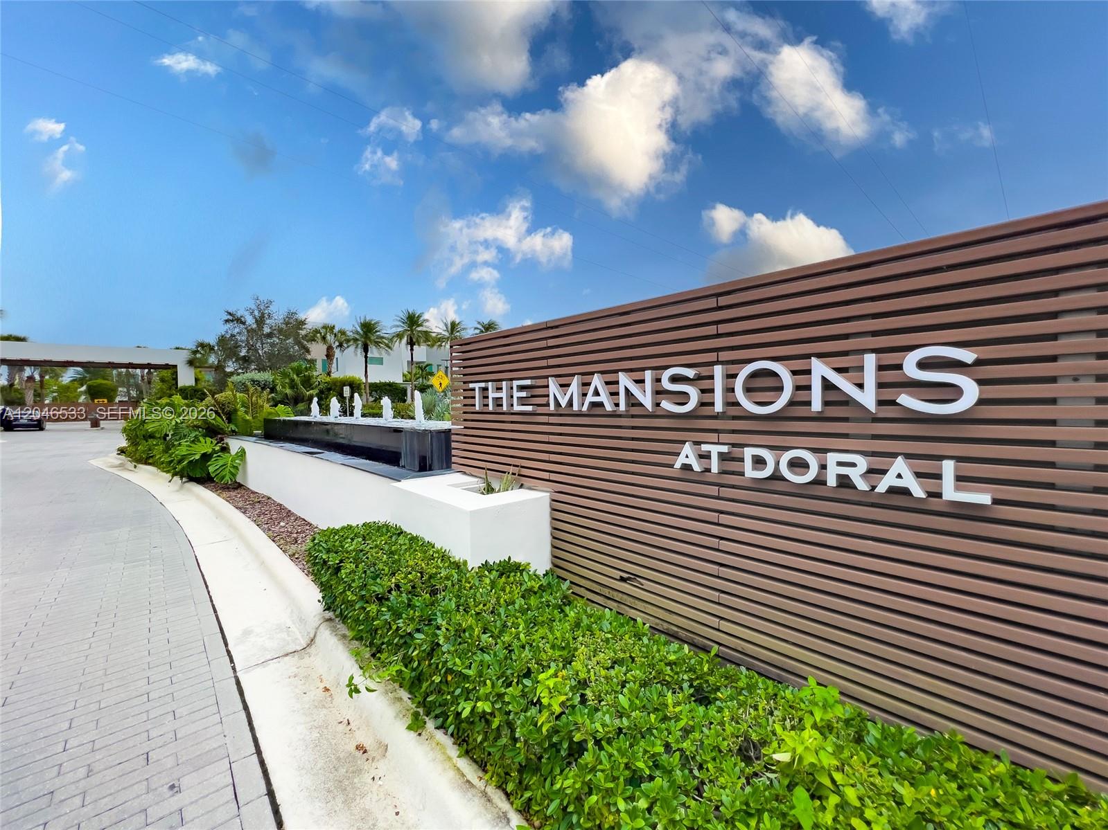 The entrance sign for The Mansions at Doral features a modern slatted wall and fountain — 10561 NW 68th Ter, Doral FL 33178, DORAL, FL