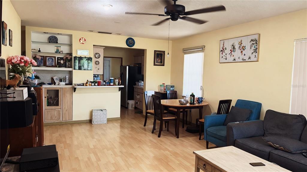 A living and dining area features light wood flooring, a ceiling fan, and yellow walls — 2515 W POWHATAN AVENUE, TAMPA, FL