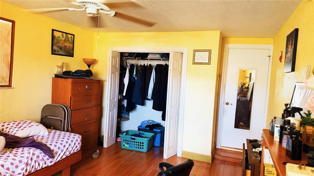 A bedroom with yellow walls, a wooden dresser, a closet, and a bed — 2515 W POWHATAN AVENUE, TAMPA, FL