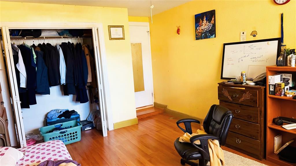 A room with yellow walls, a closet, a wooden dresser, and a desk chair — 2515 W POWHATAN AVENUE, TAMPA, FL