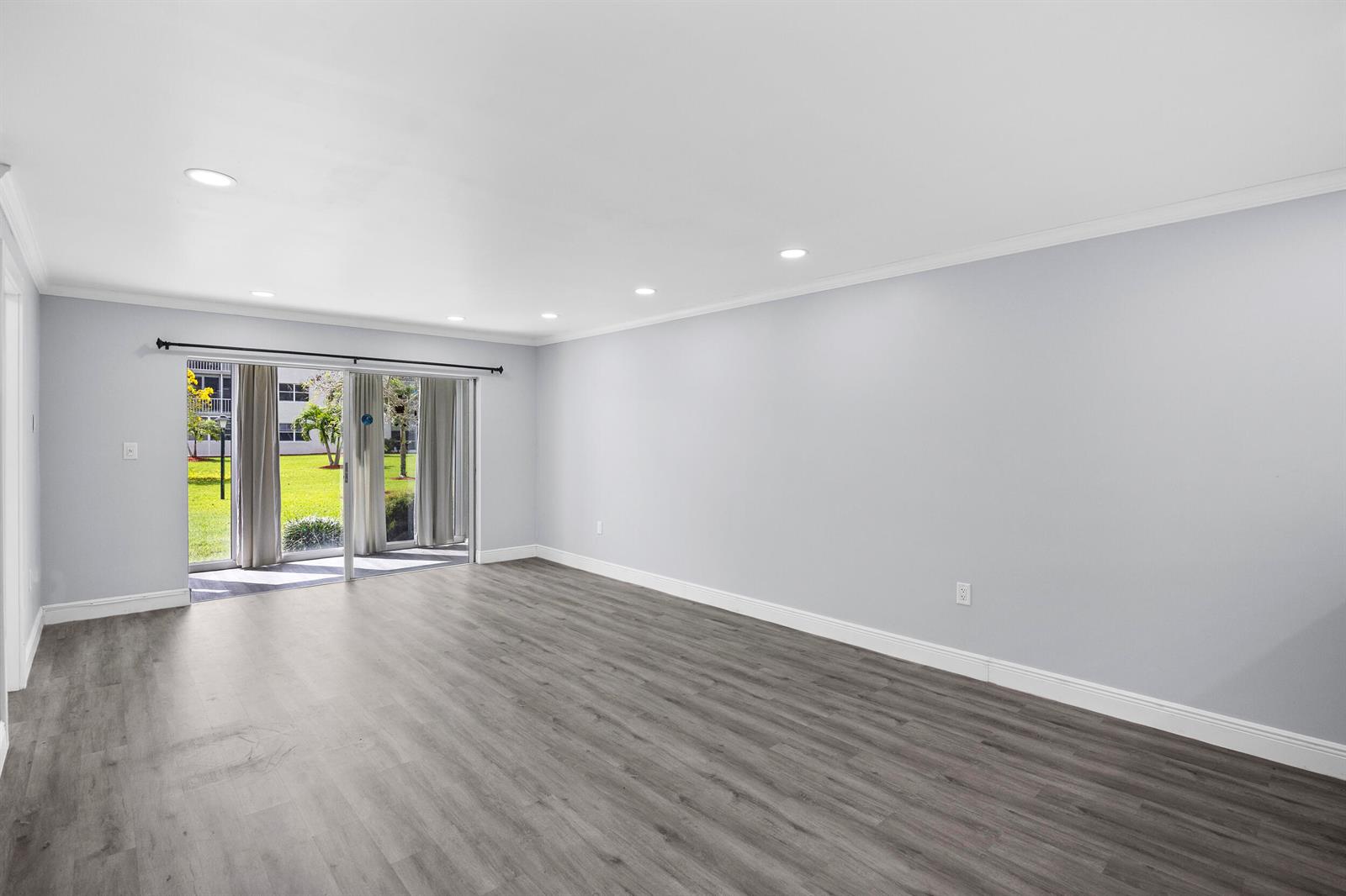 An empty room with gray walls, wood-look flooring, recessed lighting, and sliding glass patio doors — 9856 Marina Boulevard # 1314, Boca Raton FL 33428, BOCA RATON, FL